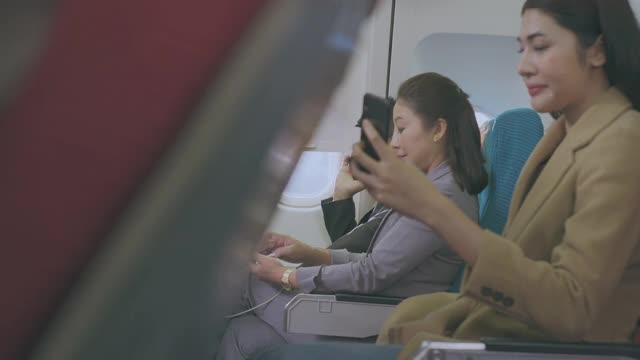 一名年轻女子在飞行中使用智能手机时大笑。视频素材