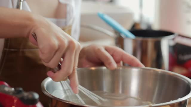 厨师用搅拌器搅拌碗里的食材。视频素材
