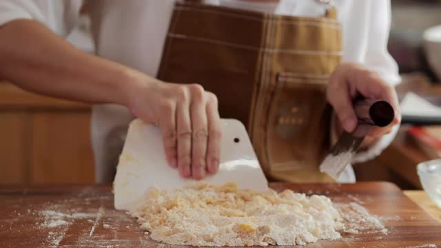 面包师双手使用刮刀，制作饼干面团，将黄油，面粉和糖搅拌在一起，在小餐馆里制作饼干。视频素材