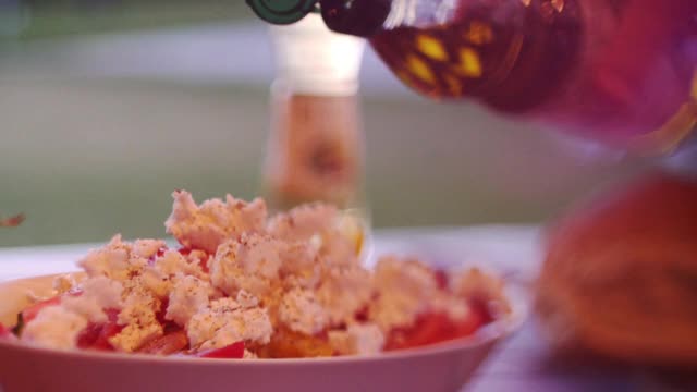 在阳光明媚的夏日，将橄榄油倒在希腊沙拉上视频素材