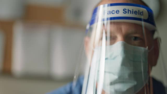 一名成熟医生摘除面罩和防护面罩的肖像视频下载