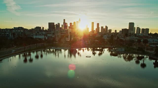 太阳在DTLA摩天大楼之间升起时，向后无人机飞越麦克阿瑟公园视频下载