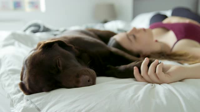 一个十几岁的女孩和她的宠物狗睡在床上视频素材