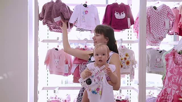 妈妈和她可爱的孩子在商店挑选衣服视频下载