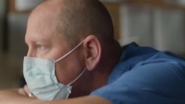 CU沉思男性护士头枕手臂取下外科口罩视频素材