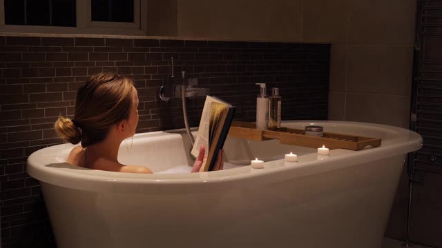 年轻女子在洗澡时看书视频素材