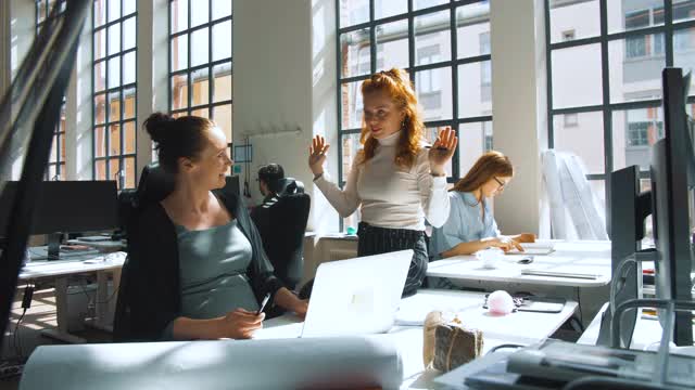 手持拍摄的女商人与女同事讨论策略对着新办公室的窗户视频素材