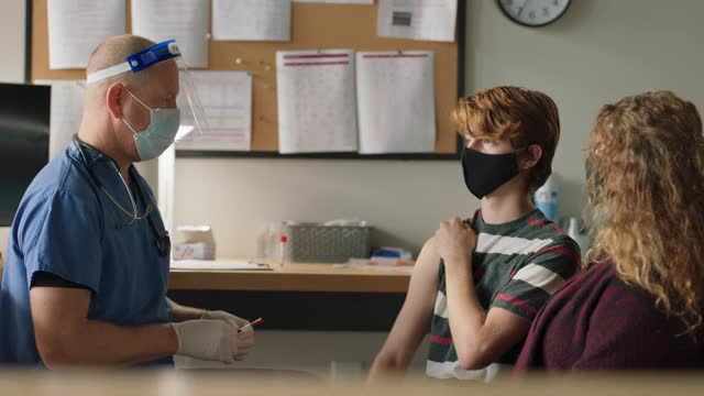 医疗保健专业人员接种青少年男孩戴防护口罩视频素材