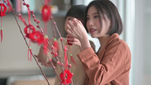 中国新年美丽的女人和她的儿子装饰房子客厅用猫咪柳和装饰准备家庭团聚视频素材