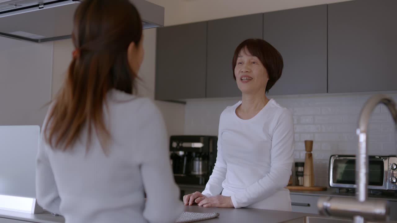 成年妇女在厨房里和年长的母亲说话视频素材