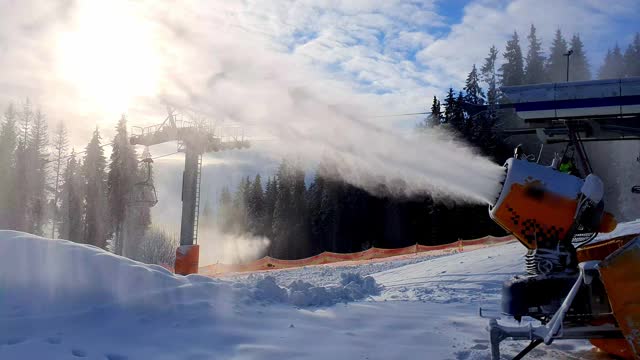 滑雪胜地的雪炮。造雪机在阳光和滑雪缆车的背景下制造人造雪。人工造雪的美妙景象。滑雪胜地的工作视频素材