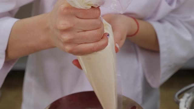 糕点师从糕点袋中挤出奶油，涂在草莓层的蛋糕上。视频下载