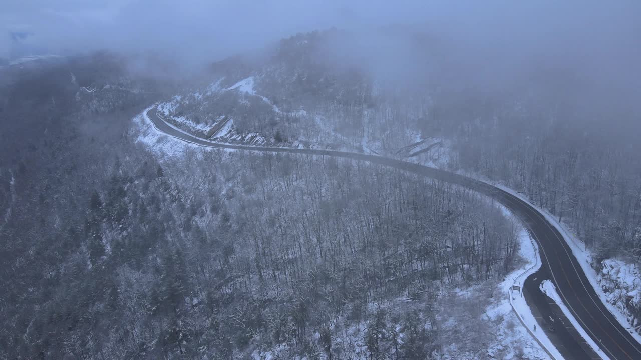 无人机拍摄的雪山高速公路上穿越云层的画面视频素材