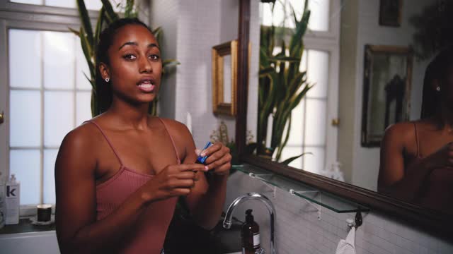 在浴室里，自信的年轻网红一边涂着睫毛膏一边解释视频素材