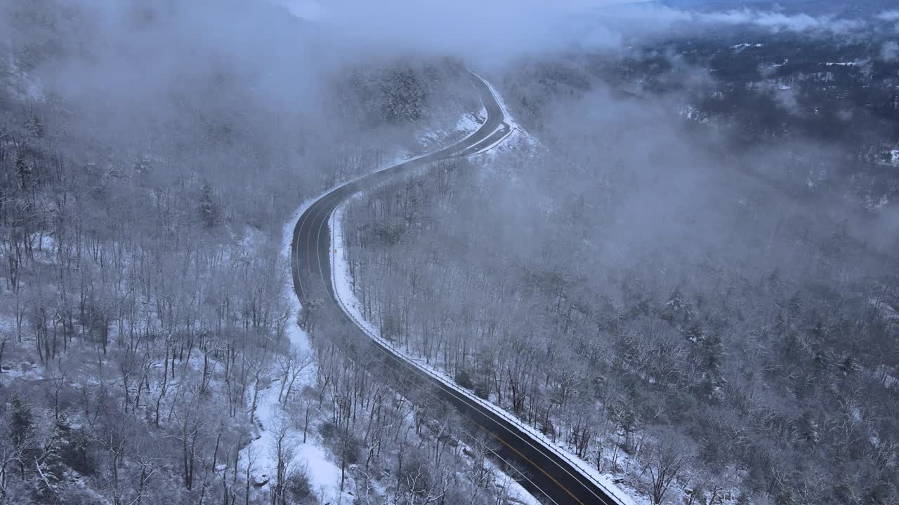 无人机拍摄的雪山高速公路上穿越云层的画面视频素材