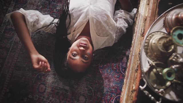 手持拍摄的年轻女性网红与长黑发躺在地毯上的家具在家里视频素材