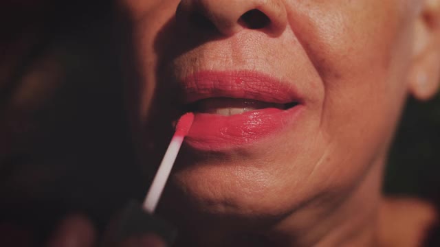 裁剪图像的退休高级妇女应用唇彩在家视频素材