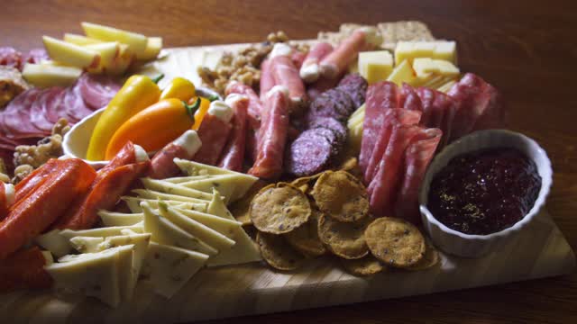 室内庆祝/派对上的一张桌子上的开胃菜熟食肉/奶酪板，上面有各种肉类，奶酪和饼干视频素材