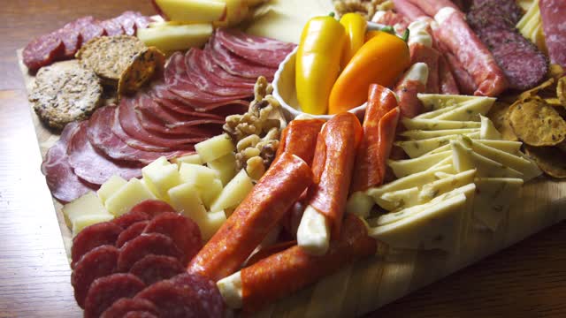 室内庆祝/派对上的一张桌子上的开胃菜熟食肉/奶酪板，上面有各种肉类，奶酪和饼干视频下载