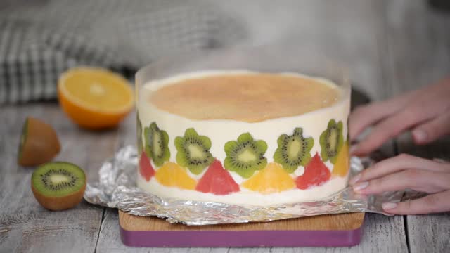 女人做美味的水果慕斯蛋糕。用新鲜水果和果冻装饰的蛋糕视频下载