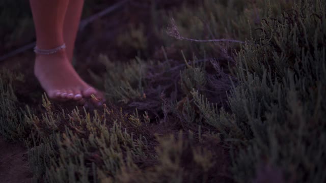 特写的年轻女子与脚链赤脚行走在自然界视频素材