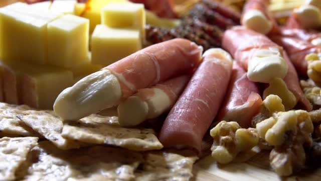 室内庆祝/派对上的一张桌子上的开胃菜熟食肉/奶酪板，上面有各种肉类，奶酪和饼干视频下载