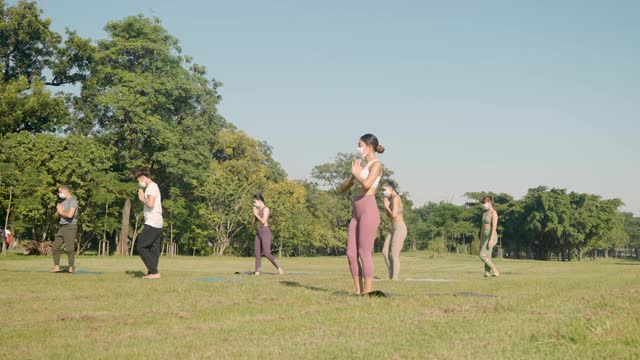 混合年龄段的人做瑜伽武士2号戴着医用防护口罩在户外做运动-隔离期间或隔离后的生活理念，冠状病毒防护措施视频素材
