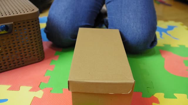 女孩坐在地板上打开一个盒子，拿出新的白色运动鞋。视频素材