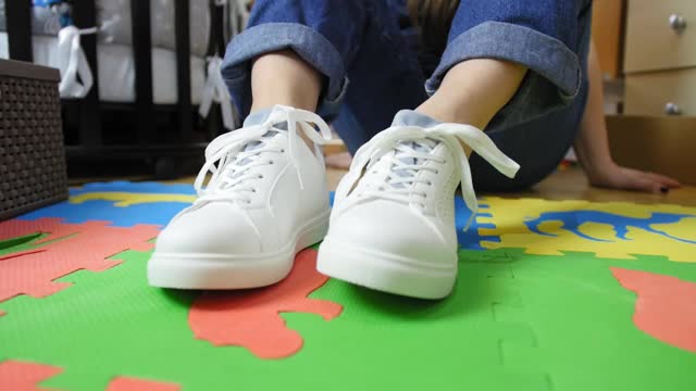 女孩穿着新的白色运动鞋和试鞋。人的双手系鞋带。视频素材