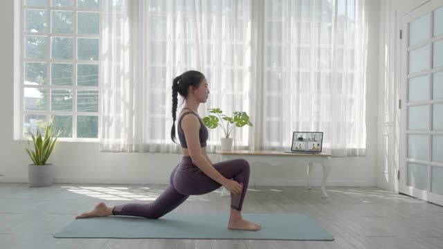 亚洲人在家通过视频会议与一群人进行虚拟健身课程。健身教练在笔记本电脑上通过视频电话上在线瑜伽课。视频下载