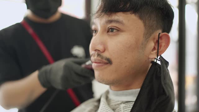 亚洲男性剪头发。在隔离封锁期间，电吹风剃须刀、盖伊理发师冠状病毒Covid-19重开业务世界大流行，企业主小企业创业视频素材
