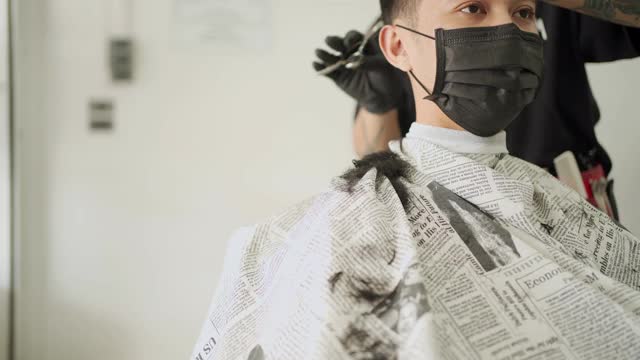 亚洲年轻人戴口罩理发，预防传染病，新的正常生活方式。2019冠状病毒病大流行重新开放业务视频素材