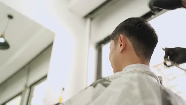 理发店内低角度拍摄，亚洲男性理发。好打扮电动理发器剃须刀剪刀，guy barber的老板在冠状病毒Covid-19重新开业小企业视频素材