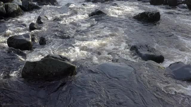这是一架无人机在苏格兰一条湍急的小河上空低角拍摄的画面视频素材