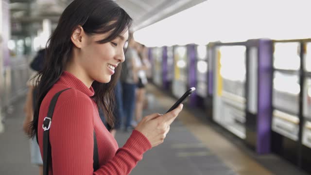亚洲女性在地铁站使用智能手机视频素材