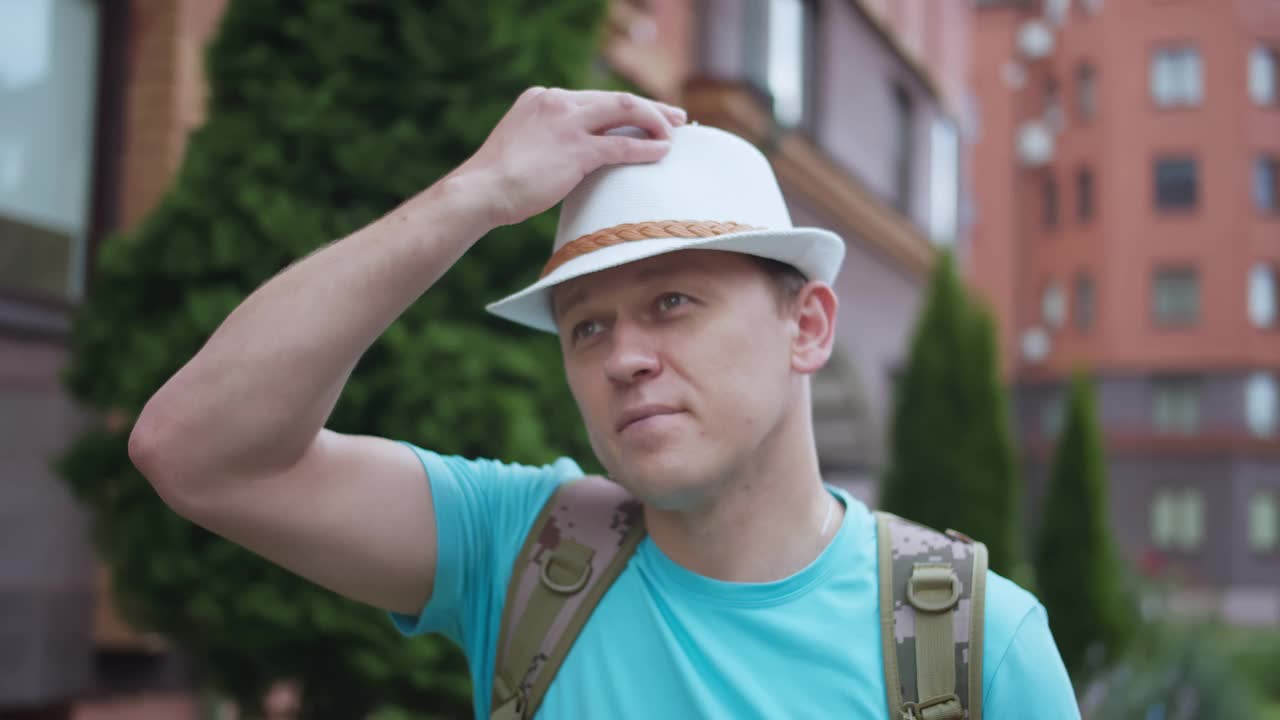 戴着帽子背着背包的年轻人在城市里走来走去，摄像头跟踪着他视频下载