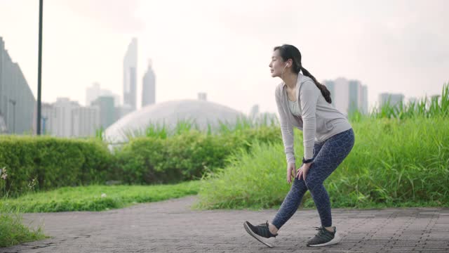 年轻的亚洲女子在城市户外跑步前做伸展运动视频素材
