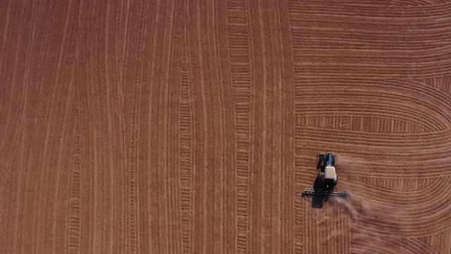 鸟瞰图的农民和农业工业拖拉机机器收获农田的土地耕作。世界在工作无人机视图概念。视频素材