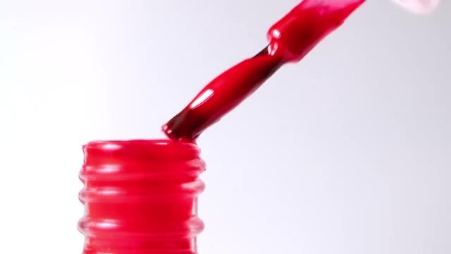 美甲师从瓶子里拿出一层红色的光滑指甲油。视频下载