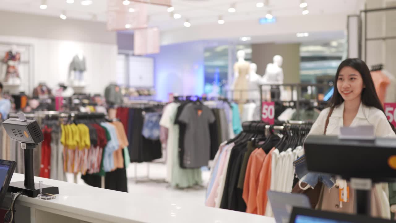亚洲华人女性购物者和她的朋友买衣服和付款柜台用信用卡视频素材