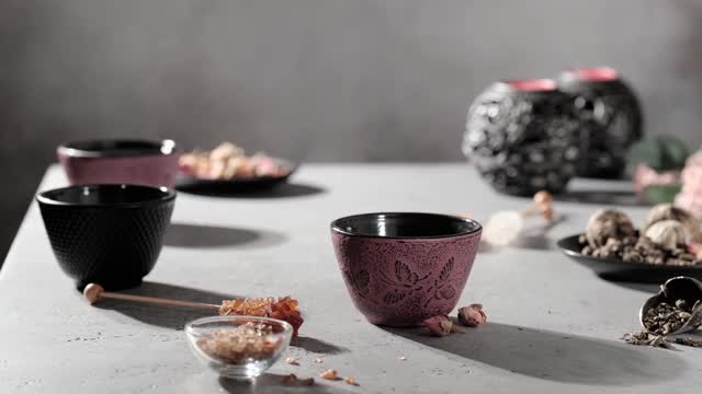 用手将黑铁茶壶中的绿茶倒入粉红茶杯中。大量的蒸汽。4 k的片段视频素材