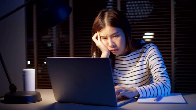 疲惫的女人坐在家里的办公桌前用笔记本电脑工作视频素材
