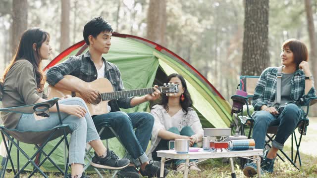 一群朋友在露营旅行中坐在帐篷外面弹吉他视频下载