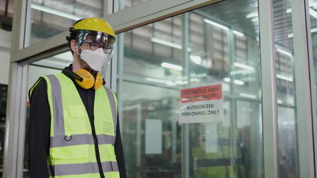 建筑工人戴上面罩，面罩对工厂员工使用体温监测仪。预防新型冠状病毒和粉尘PM2.5在工业工厂。卫生保健的概念视频素材