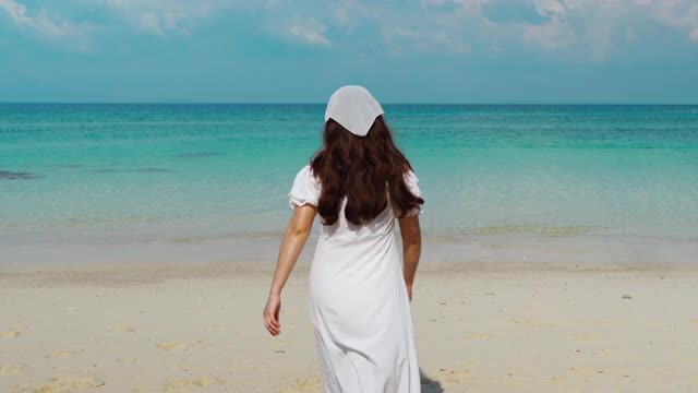 在泰国罗永州的门诺克岛的海滩上，一名快乐的妇女举起手臂走着视频素材