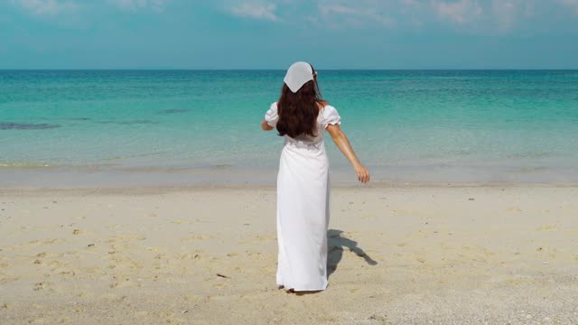 在泰国罗永州的门诺克岛的海滩上，一名快乐的妇女举起手臂走着视频素材