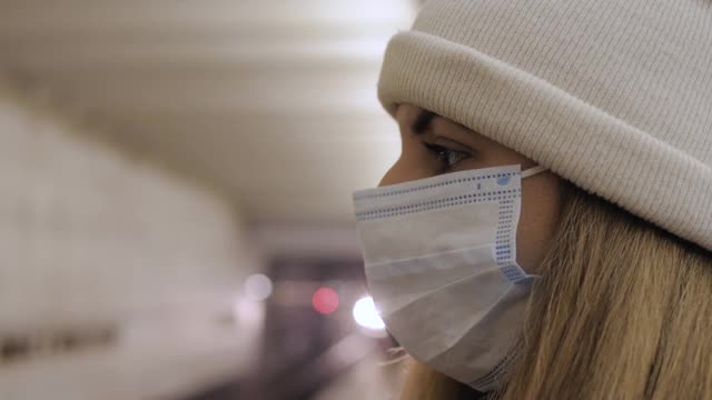 戴着医用口罩的女子在站台上等待地铁进站视频素材