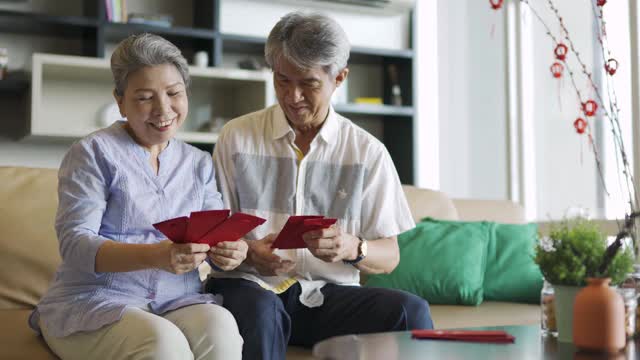 亚洲华人爷爷奶奶在家里拿着红包欢度春节视频素材