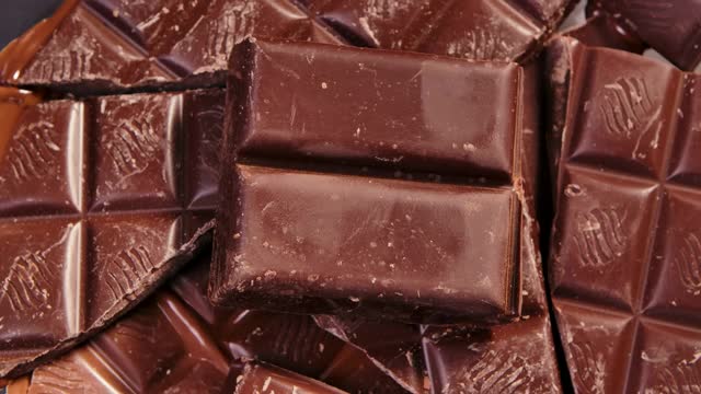 巧克力，甜巧克力块旋转，靠近。美食甜点成分。糖果,糖果的概念。纹理背景与美味的糖果。慢动作视频下载