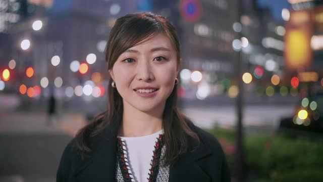 在城市的夜晚，快乐的女人对着相机微笑的肖像视频素材